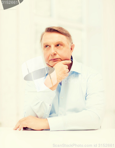 Image of stressed old man holding head at home