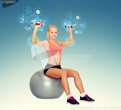 Image of woman with dumbbells sitting on fitness ball
