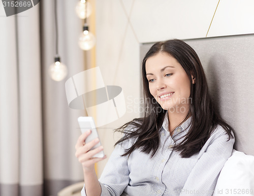 Image of happy businesswoman with smartphone in hotel room