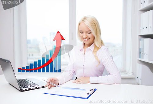 Image of smiling businesswoman with laptop and papers