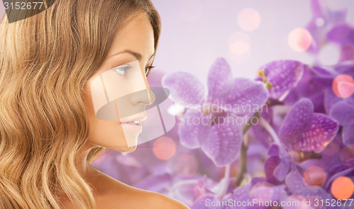 Image of beautiful young woman face over orchid background
