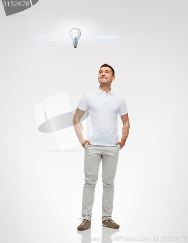 Image of smiling man looking up to lighting bulb