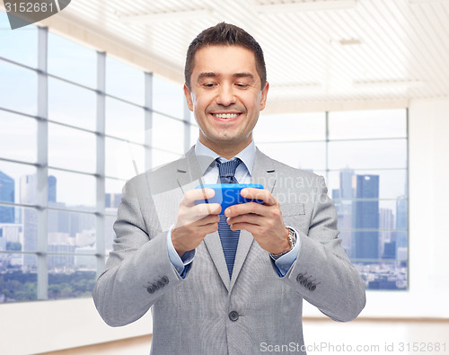 Image of happy businessman texting on smartphone