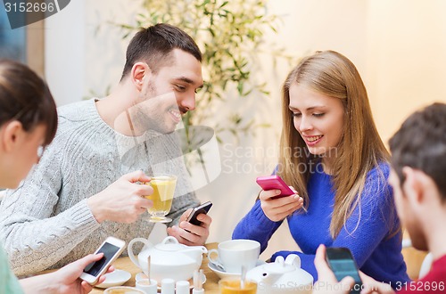 Image of group of friends with smartphones meeting at cafe
