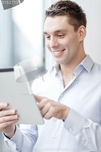 Image of smiling businessman with tablet pc in office