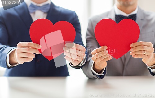 Image of close up of male gay couple holding red hearts