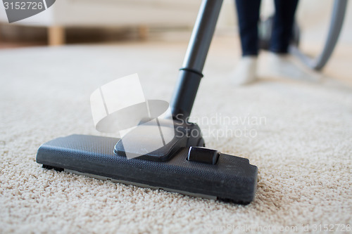 Image of close up of woman legs with vacuum cleaner at home