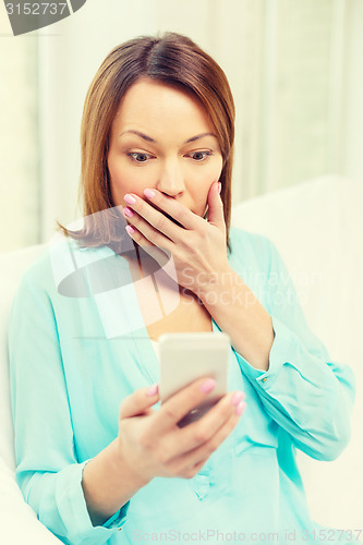 Image of surprised woman with smartphone at home