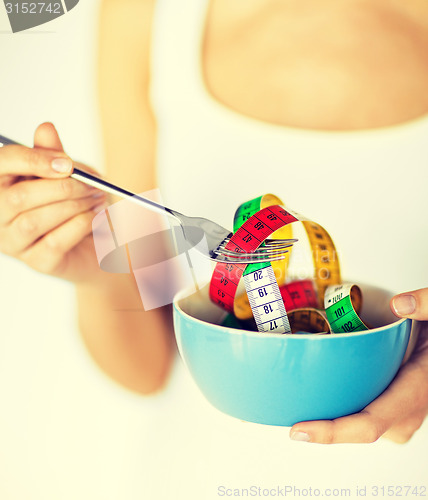 Image of woman hands holding bowl with measuring tape