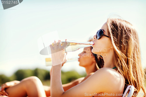 Image of girls with drinks on the beach chairs