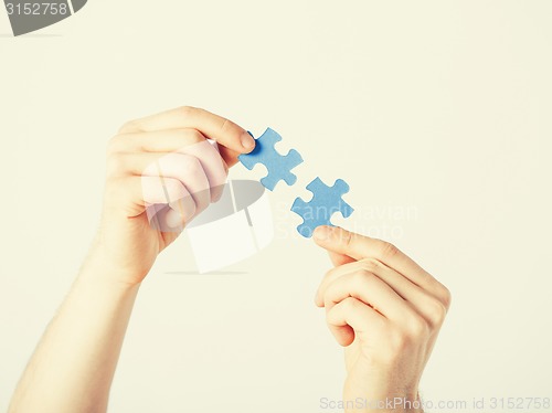 Image of two hands trying to connect puzzle pieces