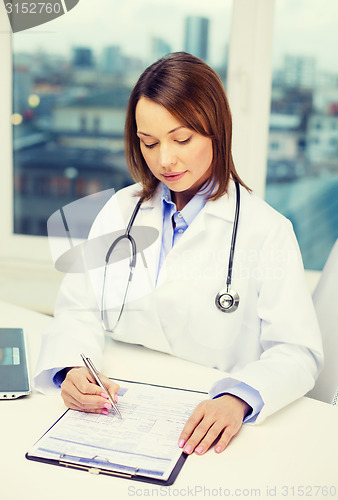 Image of busy doctor with laptop computer and clipboard