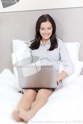 Image of happy businesswoman with laptop in hotel room