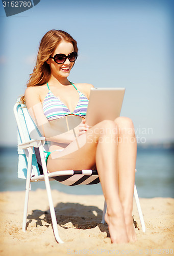 Image of girl looking at tablet pc on the beach