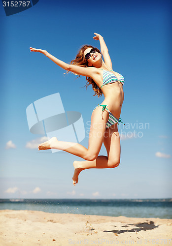 Image of woman in bikini jumping on the beach