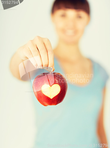 Image of woman hand holding red apple with heart shape