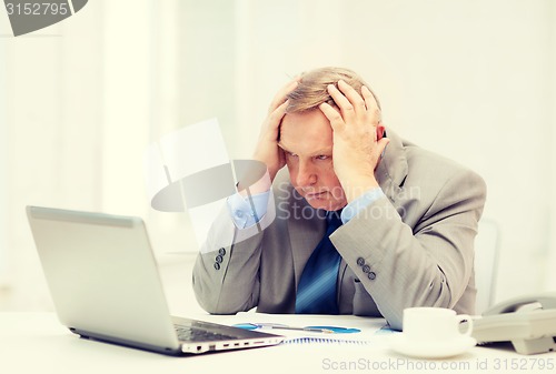 Image of upset older businessman with laptop and telephone