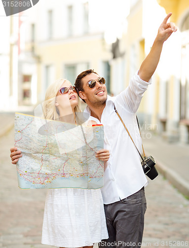 Image of smiling couple in sunglasses with map in the city