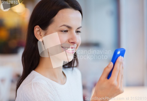 Image of close up of smiling woman with smartphone at cafe