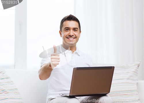 Image of happy man working with laptop computer at home