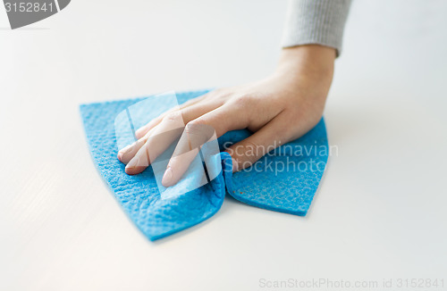 Image of close up of hand cleaning table surface with cloth