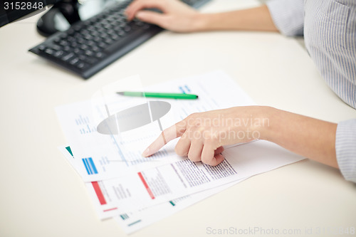 Image of close up of woman hands with papers and computer