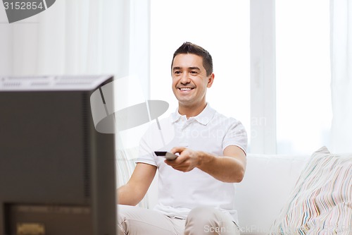 Image of smiling man with remote control watching tv