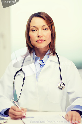 Image of busy doctor with laptop computer and clipboard