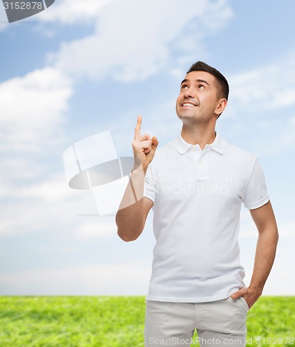 Image of smiling man in white t-shirt pointing finger up