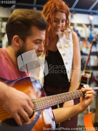 Image of couple of musicians with guitar at music store