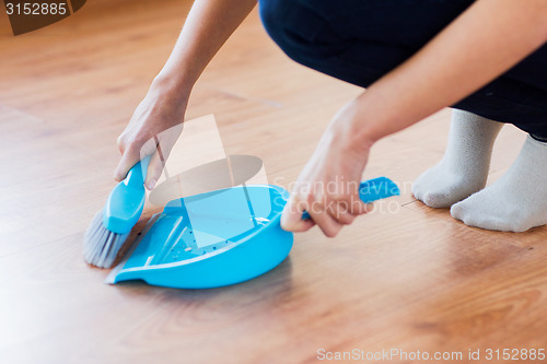 Image of close up of woman with brush and dustpan sweeping
