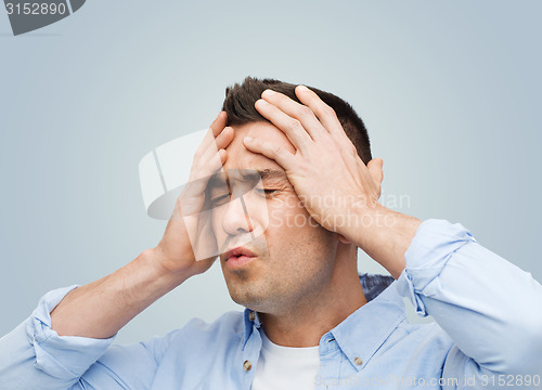 Image of unhappy man with closed eyes touching his forehead