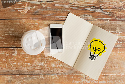 Image of close up of notebook, coffee cup and smartphone
