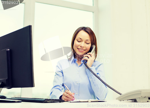 Image of businesswoman with laptop, files and telephone