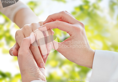 Image of close up of lesbian couple hands with wedding ring