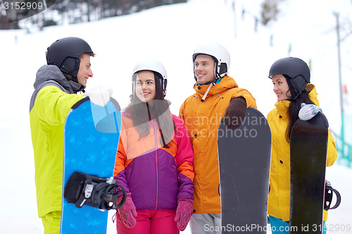 Image of happy friends in helmets with snowboards talking