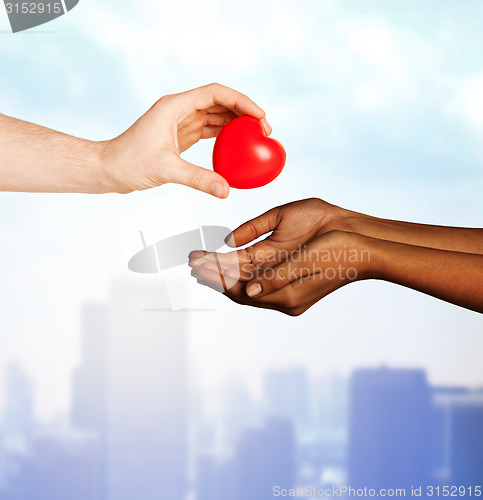 Image of woman and man hands with red heart