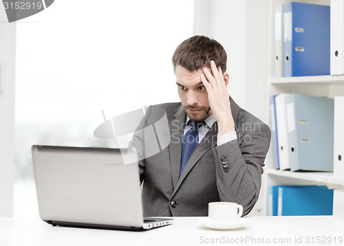 Image of busy businessman with laptop and coffee