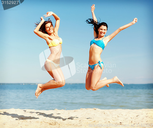 Image of girls in bikini jumping on the beach