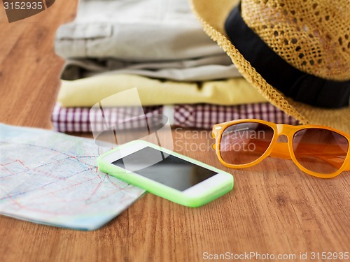 Image of close up of summer clothes and travel map on floor