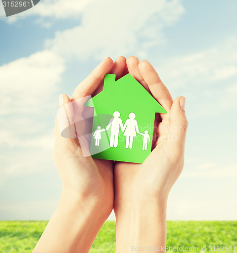 Image of hands holding green house with family