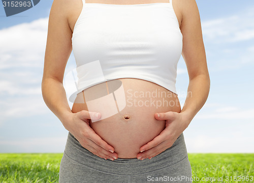 Image of close up of pregnant woman touching her bare tummy