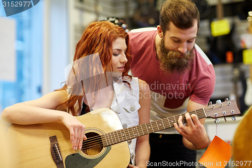 Image of couple of musicians with guitar at music store