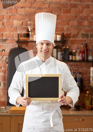 Image of happy male chef with blank menu board in kitchen