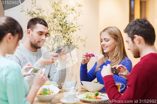 Image of friends with smartphones taking picture of food