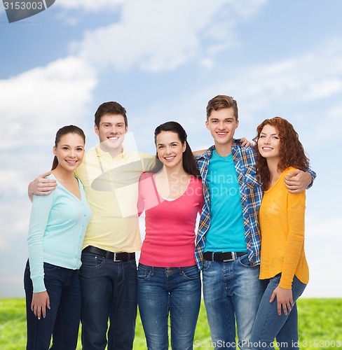 Image of group of smiling teenagers over blue sky and grass