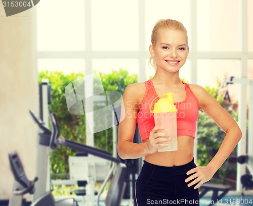 Image of smiling sporty woman with protein shake bottle