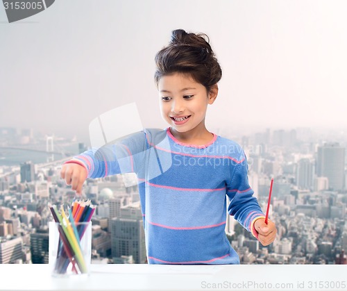 Image of happy little girl drawing with coloring pencils