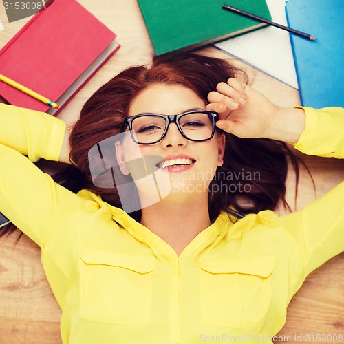 Image of smiling student in eyeglasses lying on floor