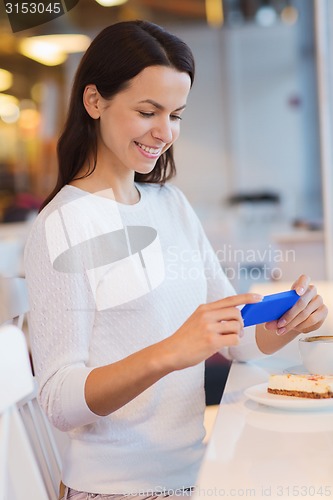 Image of smiling woman with smartphone and coffee at cafe